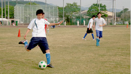 芝生の運動場で練習するサッカー部の部員たち