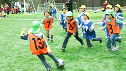 人工芝のグラウンドでサッカーを楽しむ地元園児たち