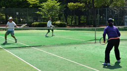 晴天の下、会話を弾ませながらプレーを楽しむテニス愛好家たち